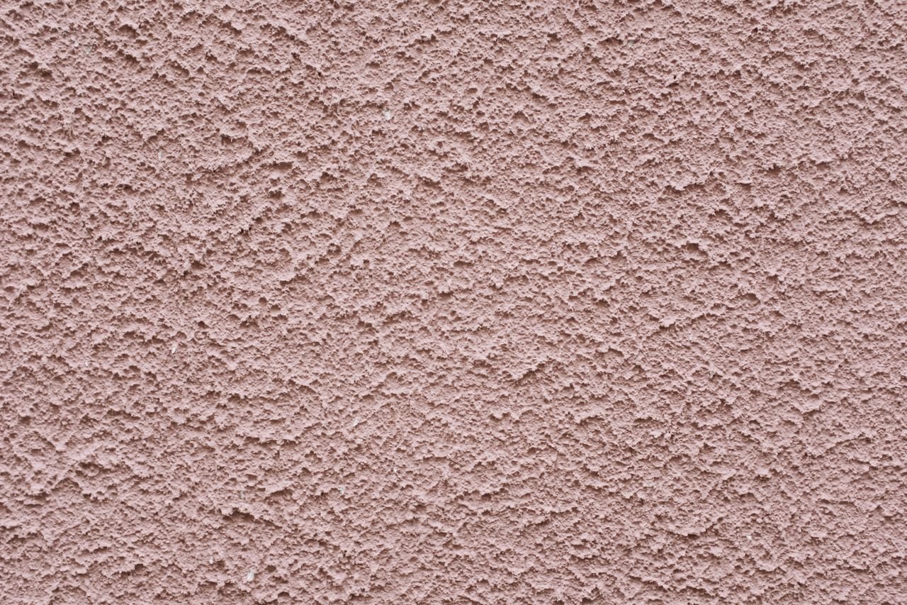 Simple background of uneven stucco pink wall surface of modern building in city