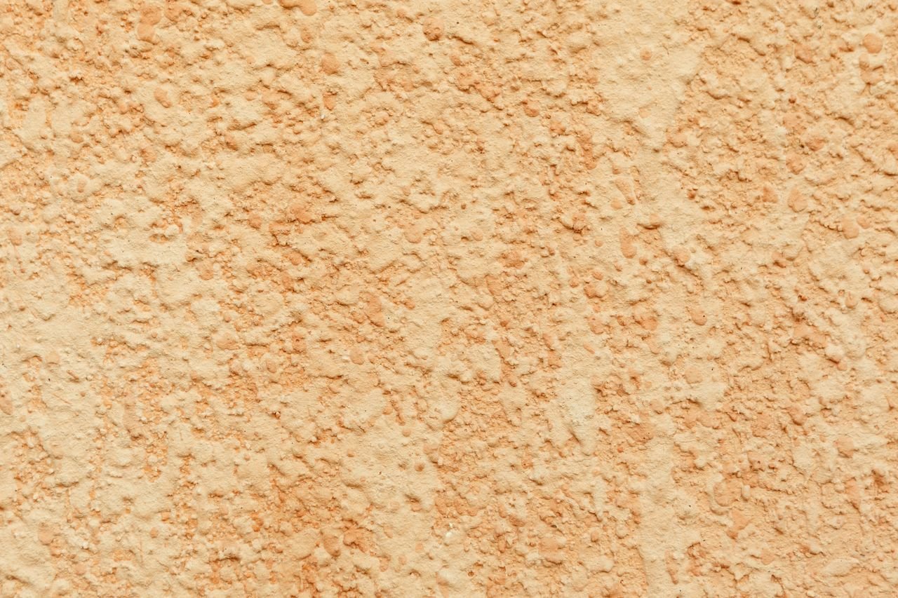 Textured background of light colored surface covered with plaster on wall of building