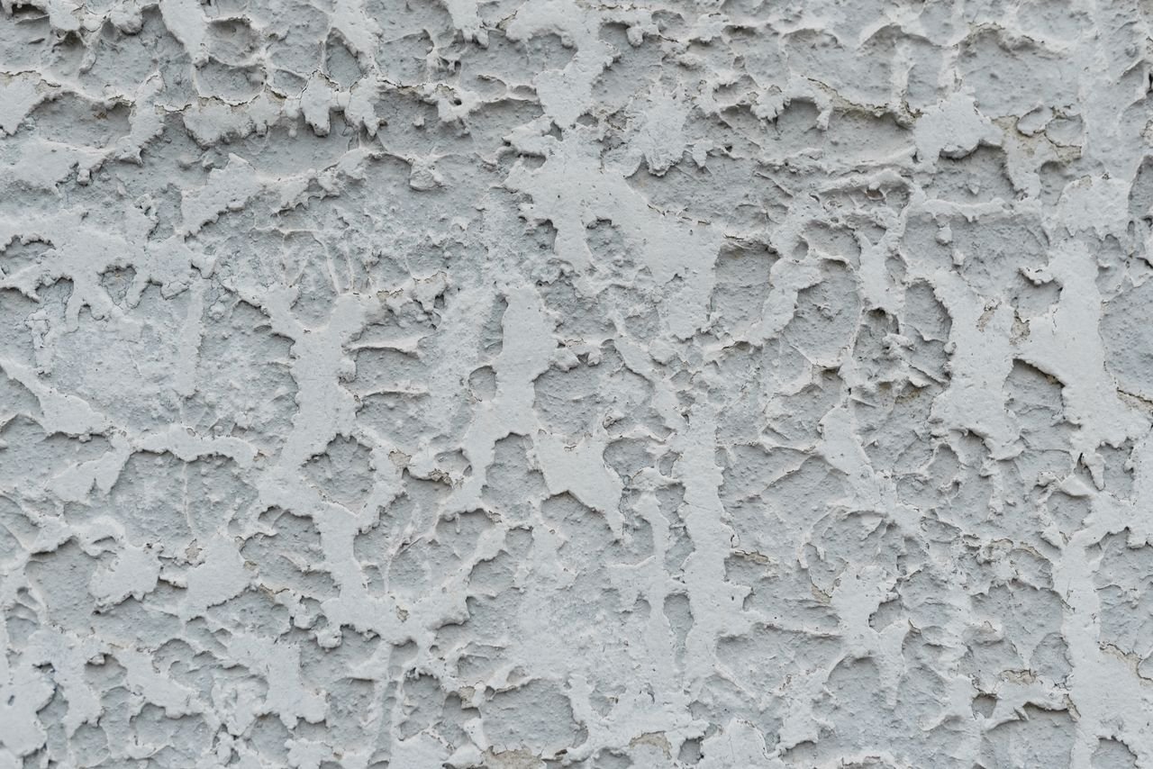 Contact Closeup of rough textured cracked surface of aged stucco wall as abstract background