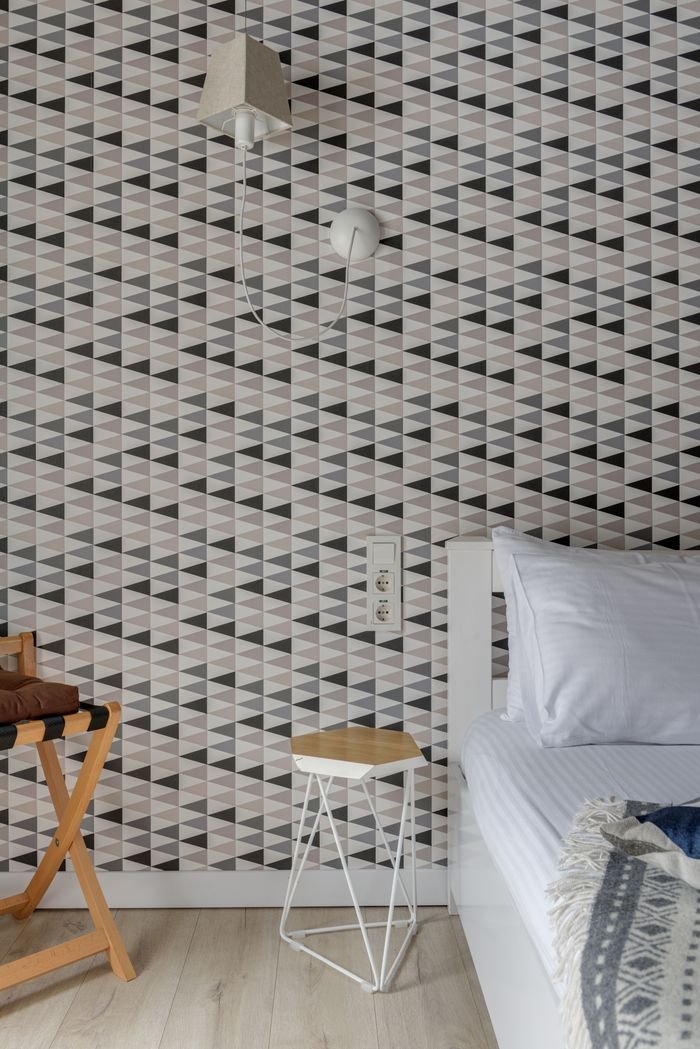 Stylish bedroom with geometric wallpaper and Scandinavian decor.